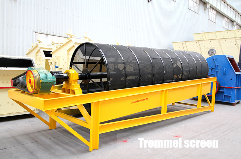 Large raw gold ore is fed by a vibrating feeder and enters a trommel screen. 